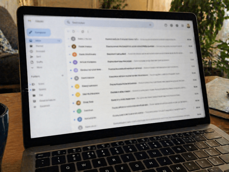 laptop displaying an email inbox on a desk in a home office setting