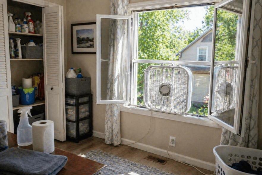 open windows with box fans for home ventilation and moisture drying in a laundry room