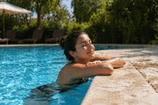 Woman relaxing in a swimming pool with arms resting on the pool edge